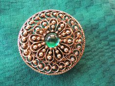 With intricate openwork surrounding a bright green glass cabochon, this bohemian brooch is a standout. Brooches are back, but this is convertable to a coat or hat pin if you want to use it that way.  It is a wonderful retro piece that will bing a pop of color gloomy winter days and fit right in with spring and summer. Measuring a bold 1 7/8" in diameter, and at over 3/4 of a century old, it is still in very nice condition, so typical of the quality of ART jewelry. Sidenote:  you hardly ever see Ornate Round Brooch With Intricate Design, Victorian Green Collectible Brooches, Ornate Round Brooches With Intricate Design, Antique Round Brooch With Intricate Design, Antique Round Brooches With Intricate Design, Antique Brooches With Intricate Design, Green Round Brooch For Formal Occasions, Green Round Brooch For Gift, Ornate Filigree Round Brooches