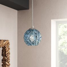 a blue glass ball hanging from a ceiling in a room with white walls and windows