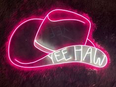 a neon sign that says yee taw on top of a cow skin surface