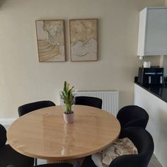 a wooden table with four black chairs and a potted plant on the table in front of it