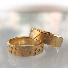 two gold wedding rings sitting on top of a table