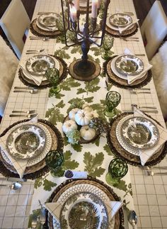 the table is set with plates and silverware, candles, and pumpkins on it