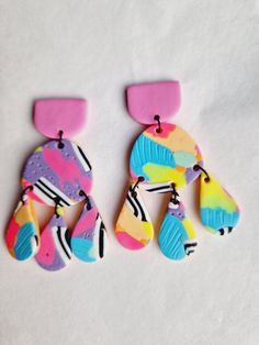 two colorful earrings are sitting on a white surface