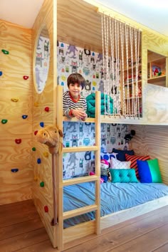 a child's bedroom with bunk beds and climbing wall in the corner, while another child sits on the bed