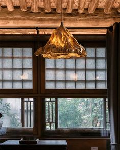 a lamp hanging from the ceiling in front of large windows with wood trimmings