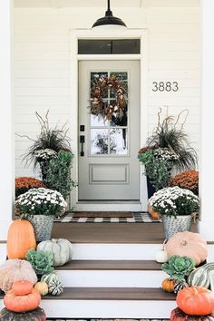 front porch decorated for fall with pumpkins and flowers