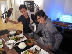 two people sitting at a table with plates of food in front of them, one holding a knife