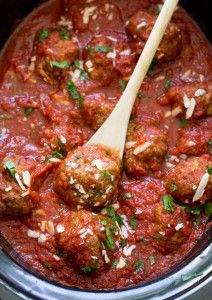 the meatballs are covered in marinara sauce and parmesan cheese with a wooden spoon