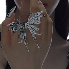 a woman is holding her hand up to the camera while wearing a ring with leaves on it