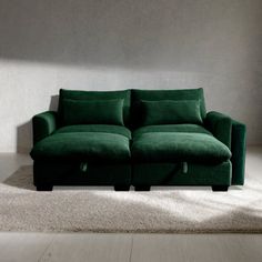 a green couch sitting on top of a white floor next to a wall and window