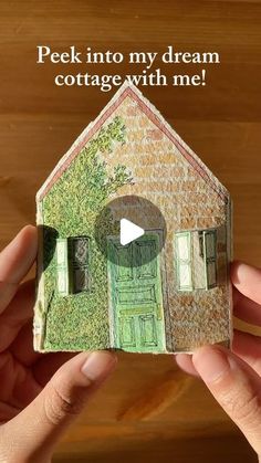 someone is holding up a small house made out of paper with the words peek into my dream cottage with me