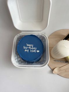 a blue birthday cake in a plastic container next to utensils and a knife