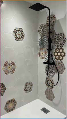 the shower head is mounted on the wall and has many different designs in it, including hexagonal tiles