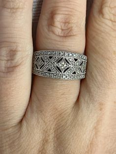 Vintage Art Deco style diamond band ring set in sterling silver. This ring features approximately 1/5 ct of glittering natural diamonds. The band measures 10 mm at the widest point and sits about 3 mm high off the finger which makes it comfortable to wear. Prongs and top of the ring are smooth and do not catch or rub. Thick amount of silver which is fully finished on the underside and stamped 925. It has been rhodium plated to prevent tarnishing. Current ring size 7.                       Items I sell are vintage and pre-worn. Any sign of wear or damage will be noted in the listing if seen. Your item will arrive professionally cleaned and in a gift box. Fine Jewelry Sparkling Diamond Stackable Rings, Fine Jewelry Diamond Stackable Rings With Sparkling Detail, Sparkling Diamond Stackable Promise Rings, Wide Band Diamond Ring With Diamond Cut, Diamond White Diamond Ring With Wide Band And Accents, Diamond Open Promise Ring, Fine Jewelry Sparkling Round Cut Diamond Ring, Dazzling Wide Band Diamond Ring, Fine Jewelry Sparkling Diamond Ring For Anniversary