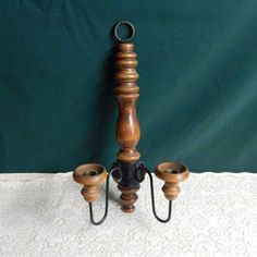 a candle holder made out of wood and metal stands on a lace covered tablecloth