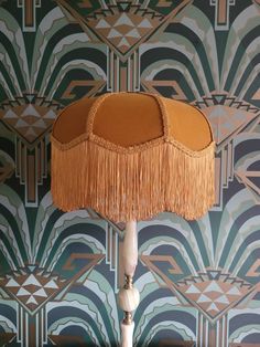 a lamp that is on top of a wooden table next to a wallpapered wall