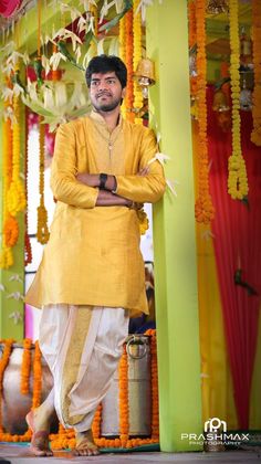 a man standing in front of a stage with flowers and garlands on the walls