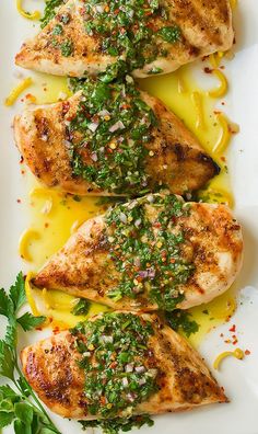 three pieces of chicken covered in sauce and garnished with parsley on a white plate