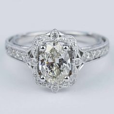 an oval cut diamond ring with pave set diamonds on the shoulders and sides, in white gold