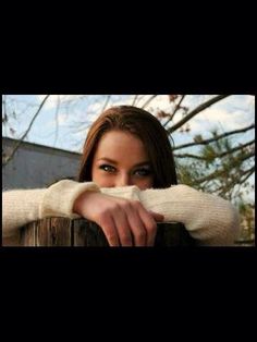 a woman leaning on a wooden fence with her hand over the top