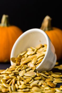 pumpkin seeds spilling out of a white cup