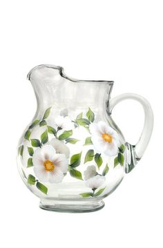 a glass pitcher with white flowers painted on it