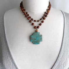 chinese turquoise cross pendant on multi strand wood bead rosary chain where are my boho cowgirls? i created this boho goodness by hand wire wrapping a chinese turquoise cross with a rhinestone spacer & a carved sandalwood lotus bead.  i added this to a necklace i made from 2 wood bead rosary chains.  so fun!  the wood beads are 2 different shapes.  this necklace is adjustable - 17" to 21".  i show the different lengths in my photos, so please see photos as they are a part of the description.  f Bohemian Turquoise Cross Necklace, Bohemian Turquoise Cross Pendant Necklace, Bohemian Brown Cross Necklace, Brown Bohemian Cross Necklace, Bohemian Cross Pendant Jewelry, Chain Cross Necklace, Turquoise Cross Pendant, Bead Rosary, Boho Cowgirl