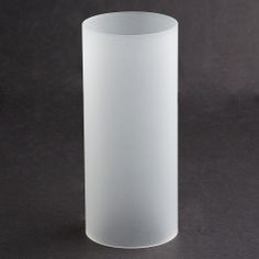 a white vase sitting on top of a black table next to a gray wall and floor