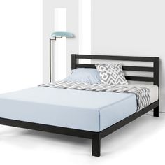 a bed that is in a room with white walls and blue sheets on top of it