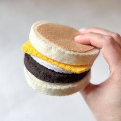 a hand holding a small hamburger made out of felt