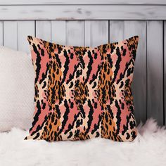 an orange and black animal print pillow sitting on top of a white fur covered bed