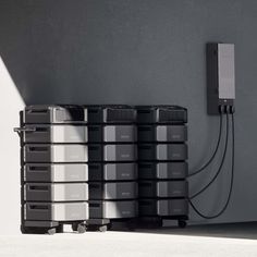 several black and white containers sitting next to each other in front of a gray wall