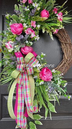 a wreath with pink flowers and greenery on the front door