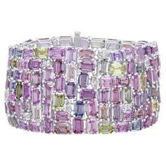 This extravagant, gorgeous bracelet features 119.06 carats emerald cut and oval cut sapphires, including pink, yellow, green, lavender, and light blue. 3.68 carats marquise and round cut natural diamonds are tucked inside the densely packed array. The bracelet measures 7" in length and is set in 18k White Gold. GIA Certification has been obtained on the finished piece. The certificate will be provided with your purchase. (photo included for reference) GIA certification represents one of the high