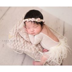 a newborn baby is wrapped in a blanket and wearing a flower headband with her eyes closed