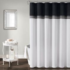 a white and black shower curtain next to a bath tub with a mirror on the wall