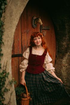 a woman with red hair wearing a dress and holding a basket in front of a door