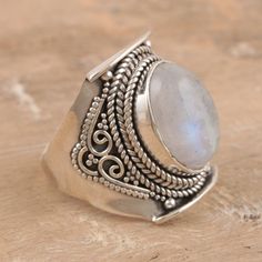 With its pale, iridescent gemstone, Rakesh Rana's impressive cocktail ring will give you the glamour you've been craving. Indian artisans use sterling silver to hand craft the ring, centering its band with a smooth rainbow moonstone in a raised bezel setting. Handmade Silver Moonstone Ring Fine Jewelry, Silver Fine Jewelry Rings With Moonstone, Silver Moonstone Rings In Fine Jewelry Style, Silver Moonstone Ring In Fine Jewelry Style, Unique Moonstone Rings With Gemstone Accents, Artisan Silver Moonstone Ring, Silver Fine Jewelry Moonstone Open Ring, Silver Mystical Moonstone Ring, Silver Moonstone Open Ring Fine Jewelry