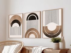 three framed art pieces hang on the wall above a wicker bench with a plant