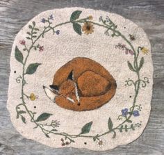 an embroidered coaster with a sleeping fox on it