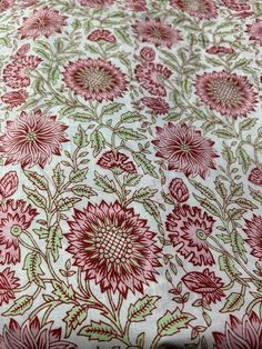 a red and green floral print on white fabric