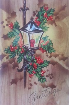 a christmas card with a lit candle and holly wreath on the front, hanging from a wooden background