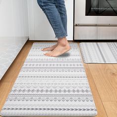 a person standing on a kitchen rug in front of an oven with their feet up