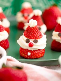 some strawberries with white frosting and santa hats on them are sitting on a green plate