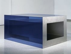 a blue box sitting on top of a white floor next to a wall with an opening in it