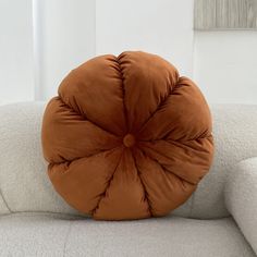 a round pillow sitting on top of a white couch