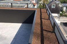 the roof is covered with brown mulch and there are many buildings in the background