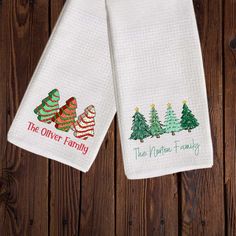 two white kitchen towels with christmas trees and the words, the oven family on them