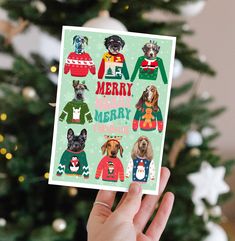 someone holding up a christmas card with dogs in sweaters on it and the words merry