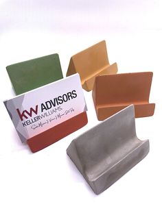 four different colored soap bars sitting next to each other on a white surface with a business card in front of them